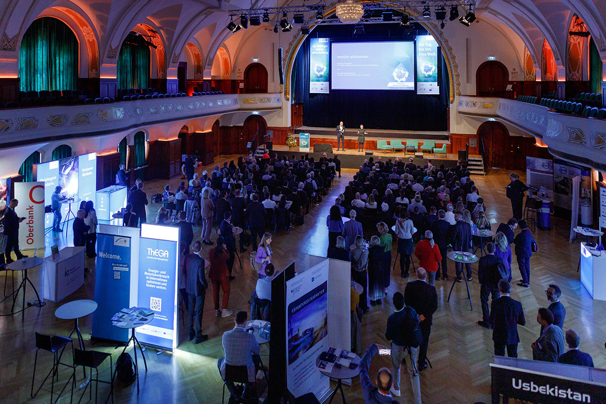 Das Publikum des 18. Thüringer Außenwirtschaftstages steht vor einer Bühne mit Pröstentationsleinwand.